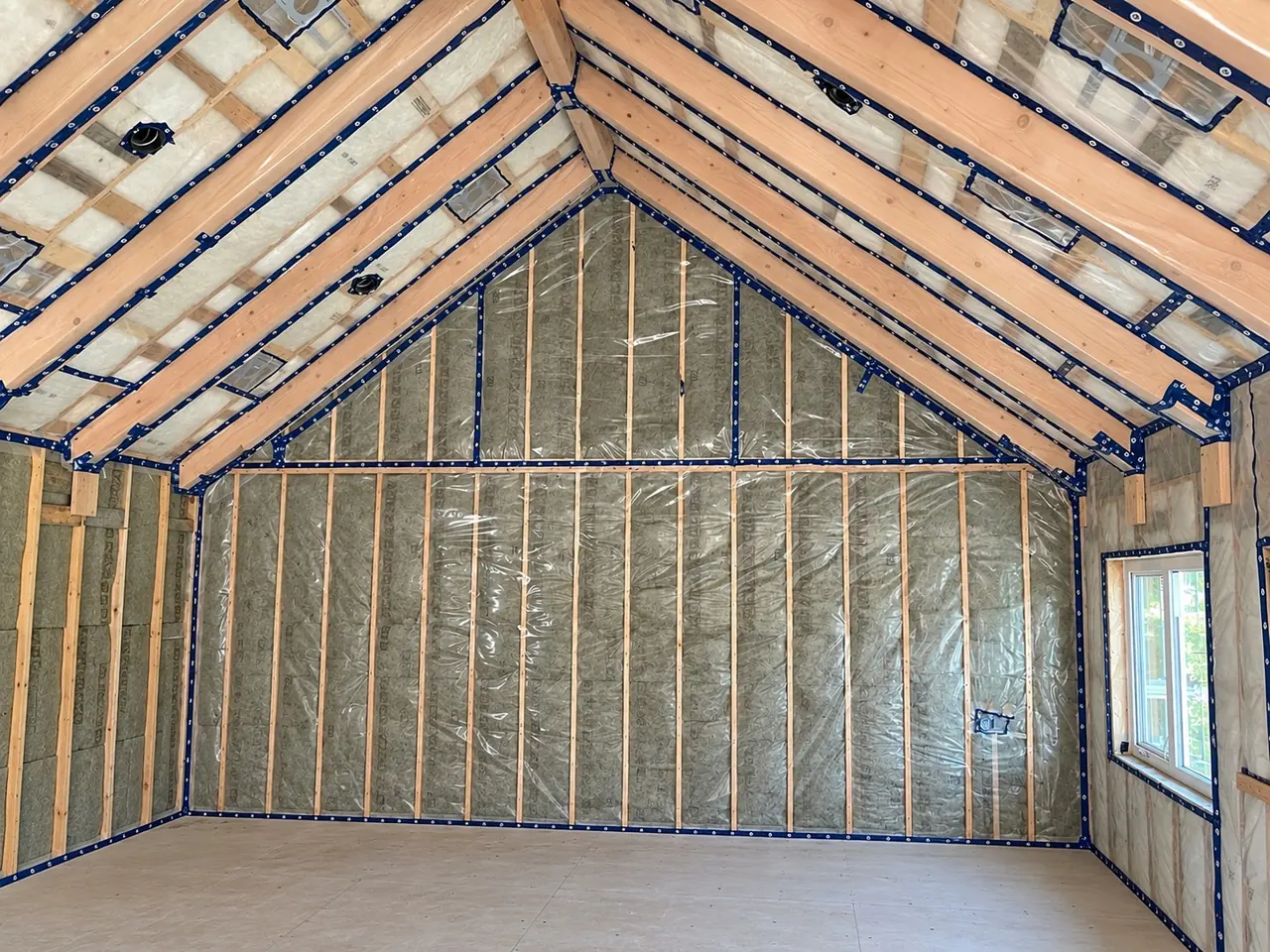 Vaulted attic framed with wood trusses, insulation batts and a sealed vapour barrier in place.