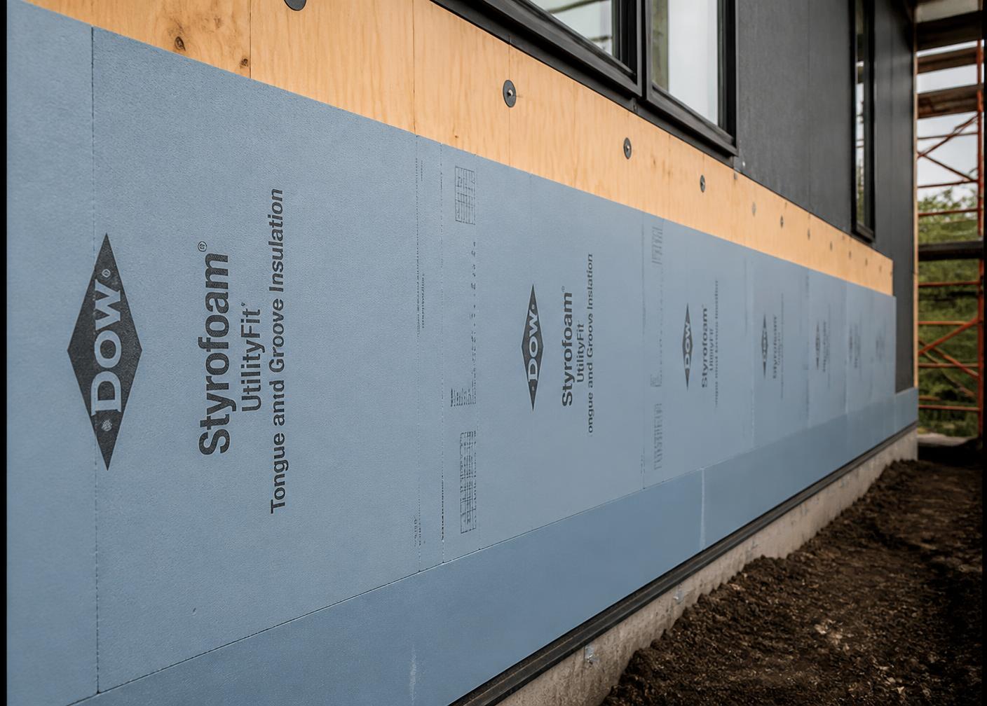 Continuous rigid exterior insulation being installed over sheathing on a high-performance building wall